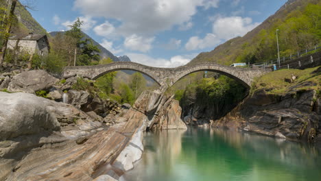 Low-angle-looking-up-to-Tourists-explore-and-gather-taking-pictures-on-Ponte-Dei-Salti-in-Lavertezzo-Verzasca-Switzerland