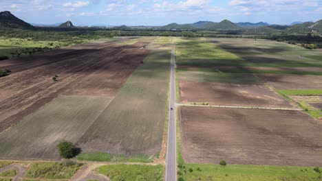 Eine-Luftaufnahme-Einer-Drohne-Eines-Blauen-Toyota-Chr-Fahrzeugs,-Das-Auf-Einer-Geraden-Straße-In-Der-Landschaft-Von-Lopburi,-Thailand,-Fährt