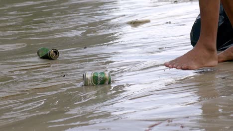 Bahía-De-Ha-Long,-Vietnam---Un-Hombre-Está-Recogiendo-Dos-Botellas-De-Lata-En-La-Orilla-Para-Guardarlas-En-Su-Bolsa-De-Basura-Negra---Cerrar