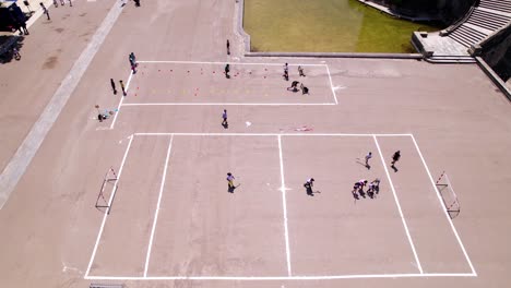 Aerial-shot-overhead-children-playing-hockey-on-marked-concrete-in-Montpellier