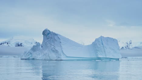 Gran-Puesta-De-Sol-Del-Paisaje-Marino-Del-Iceberg-De-La-Antártida,-Grandes-Icebergs-Azules-Masivos-Con-Formas-Asombrosas-Y-Nubes-Dramáticas-Y-Cielo-En-El-Paisaje-Invernal-Del-Amanecer-En-La-Península-Antártica-En-Una-Escena-Helada