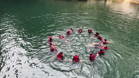 Participantes-De-Rafting-Usando-Chalecos-Salvavidas-Y-Haciendo-Círculos-Juntos-En-El-Río-De-Montaña.