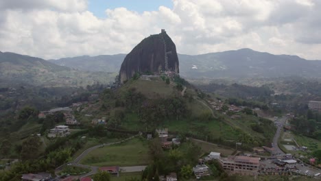 Orbit-shot-of-El-Peñón-de-Guatapé,-a-large,-unique-rock-standing-alone-with-stairs-to-the-top-and-offering-panoramic-views,-Guatapé,-Colombia
