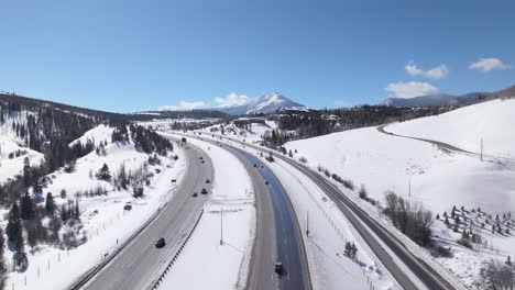 Traffic-on-highway-surrounded-by-snow,-winter-in-Colorado,-sunny-day