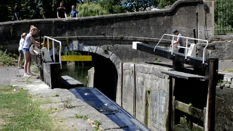 Altes-Englisches-Narrowboat,-Das-Durch-Den-Kanallift,-Breite-Schleusen-Und-Unter-Einer-Brücke-Hindurchfährt