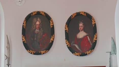 Portraits-of-noble-figures-with-decorative-golden-frames,-flanked-by-historical-weapons-in-Trakoscan-Castle,-Croatia