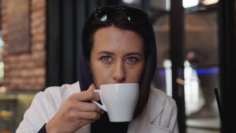 Thoughtful-caucasian-brunette-drink-cup-of-coffee-at-indoor-cafe,-Prague