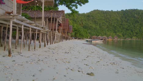 Wooden-cottages-on-the-sandy-shores-of-Kri-Island-in-the-Raja-Ampat-Archipelago-of-Indonesia,-marred-by-the-unfortunate-sight-of-two-plastic-bottles-littering-the-pristine-landscape