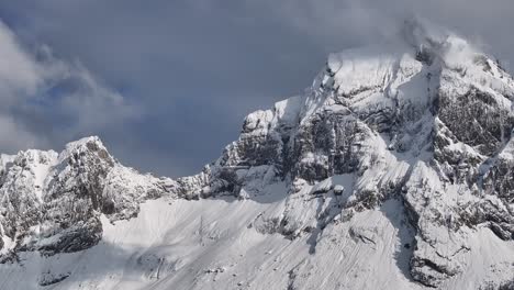 Vista-Aérea-Del-Pico-Fronalpstock-Cubierto-De-Nieve-Con-Acantilados-Escarpados-Y-Un-Cielo-Parcialmente-Nublado-En-Glarus-Nord,-Suiza