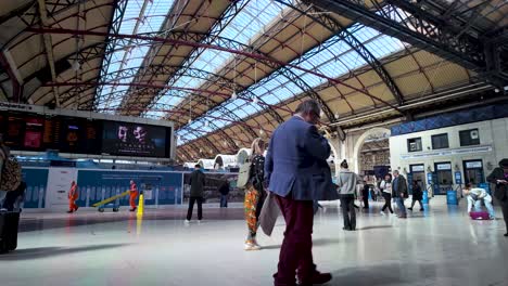 Estación-Victoria-De-Londres-Repleta-De-Viajeros-Bajo-Un-Gran-Techo-Arqueado,-Tablero-De-Horarios-De-Trenes-Visible,-Atmósfera-Dinámica,-Mediodía,-Plano-General