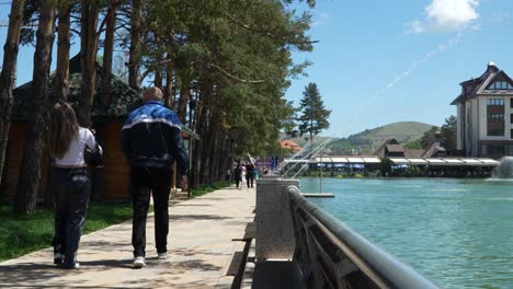 Waterfront-with-people-walking-along-a-tree-lined-path,-Zlatibor