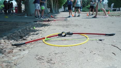 Slow-motion-shot-of-an-archery-bow-and-arrow-placed-on-the-ground-beside-kids