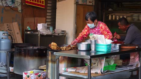 Una-Abuela-Prepara-Y-Vende-Deliciosa-Comida-Callejera-Taiwanesa-En-El-Mercado-Local,-Capturando-En-Cámara-Lenta-La-Cultura-De-La-Comida-Callejera-En-Asia