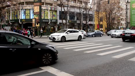 Escena-De-Una-Calle-Muy-Transitada-En-Bucarest-Con-Coches-Cruzando-Una-Intersección-En-Un-Día-Nublado,-Ambiente-De-La-Ciudad.