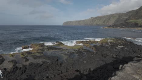 People-exploring-volcanic-rocks-on-mosteiros-beach,-Sao-Miguel-with-waves-crashing,-aerial-view