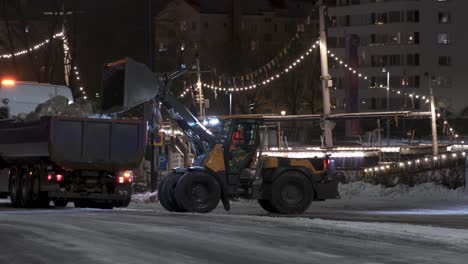 Man-driving-a-front-end-loader-and-loading-up-snow-on-a-truck