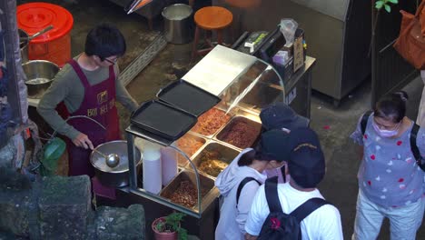 People-lineup-to-buy-famous-freshly-made-A-Gan-Yi's-Taro-balls-dessert-at-Jiufen's-old-street-in-the-charming-mountain-village-town,-a-popular-tourist-attraction-of-Taiwan