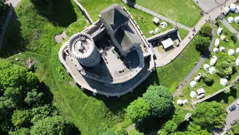 Medieval-castle-with-a-turret,-walls,-and-courtyard-during-a-beautiful-summer-day-surrounded-by-lush-greenery,-grass,-and-trees
