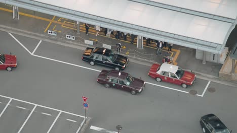 Passengers-coming-out-of-train-station-and-taking-cab,-Kyoto,-Japan-High-angle-time-lapse