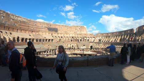 camera-walks-inside-the-Colosseum-in-Rome,-Italy-on-a-beautiful-day-in-spring-with-blue-sky-and-white-clouds