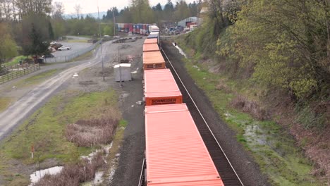 Stacked-shipping-containers-on-freight-train-slowly-pass-directly-below-camera