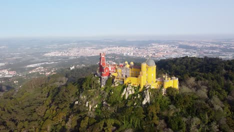 Colorido-Palacio-De-Pena-En-Sintra,-Portugal,-Rampa-De-Velocidad-Retrocede-A-Un-Amplio-Paisaje:-Vista-Aérea-De-Drones,-Brillante-Castillo-Cerca-De-Lisboa,-Día-Soleado