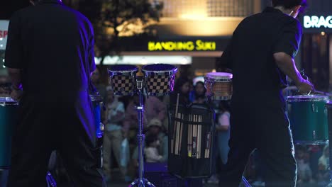 Back-view-of-two-young-man-musician-playing-drums-and-percussion-instruments-together-in-front-of-audience