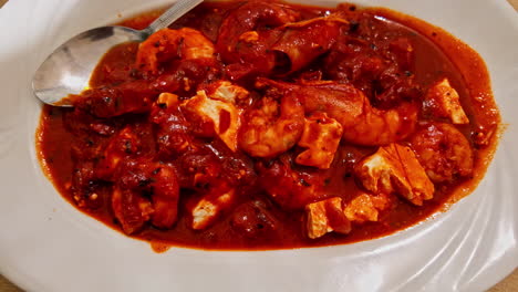 Close-up-shot-of-delicious-traditional-greek-dish-garides-saganaki-served-in-a-white-plate-on-a-restaurant-table-in-Greece