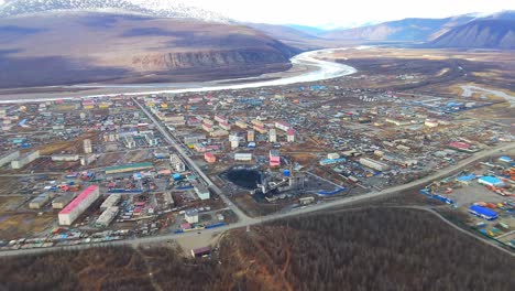 A-small-town-against-the-backdrop-of-mountains-covered-with-snow-from-a-drone