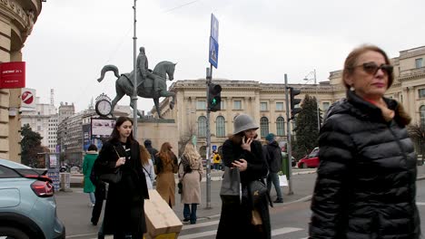 Bustling-street-scene-in-Bucharest-with-pedestrians-and-equestrian-Carol-I-of-Romania-statue