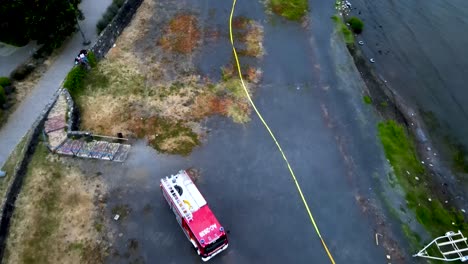 Plataforma-Rodante-Aérea-De-Camión-De-Bomberos-Y-Bomberos-Trabajando-En-Operación-Cerca-De-La-Orilla-Del-Lago-Durante-El-Día-En-Pucón,-Chile.