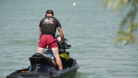 Tracking-shot-of-lifeguard-guide-on-jet-ski-observing-lake-of-free-style-water-park-during-sunlight