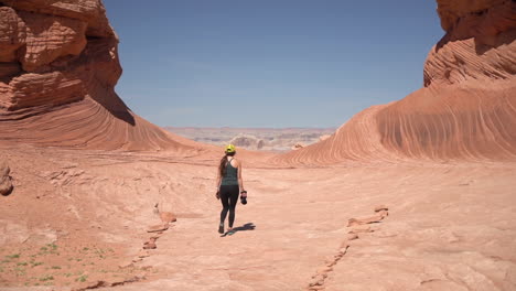 Mujer-Solitaria-Con-Cámara-Fotográfica-Caminando-Bajo-Formaciones-De-Arenisca-Lavada-En-El-Parque-Nacional-Del-Gran-Cañón,-Arizona,-EE.UU.