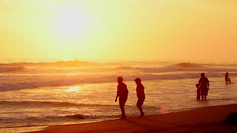 Sonnenuntergang-Am-Strand,-Während-Die-Leute-Das-Meer-Genießen