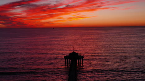 Silhouetted-Roundhouse-Aquarium-At-Manhattan-Beach-Pier-During-Red-Sunset-In-California,-USA