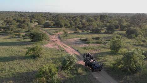 Aerial-push-in-shot-of-safari-vehicle-driving-on-dirt-road-on-African-savanna