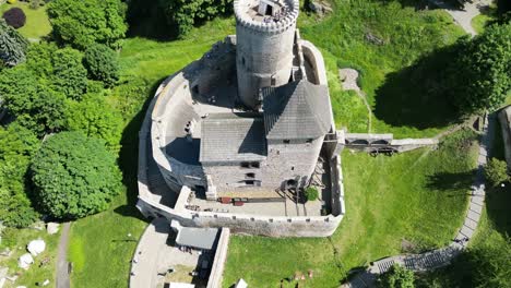 Medieval-Bedzin-castle-with-a-turret,-walls,-and-courtyard-during-a-beautiful-summer-day-surrounded-by-lush-greenery,-grass,-and-trees