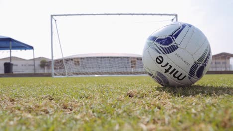 Football-soccer-ball-roll-to-right-of-frame-with-goalpost-behind