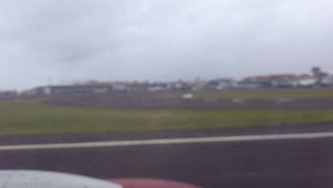 View-of-airplane-taking-off-looking-out-of-passenger-window-at-runway-while-taking-off-from-Bali-airport-on-a-cloudy-day