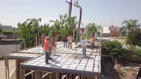 Antena-Sobre-El-Techo-Vertiendo-Cemento-Para-Construir-Una-Estructura-De-Techo-O-Piso-Usando-Chalecos-Naranjas-Como-Trabajadores-De-La-Construcción-Trabajando-En-El-Sitio