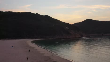 Sai-Kung-village-Hong-Kong-idyllic-sandy-beach-aerial-view-under-green-island-mountain-range-dolly-right