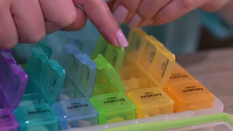 Woman-carefully-placing-prescribed-medications-in-pill-organizer,-organizing-daily-pills