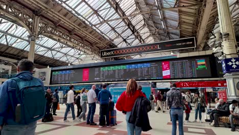 Observing-the-interior-of-London-Victoria-Station-concourse,-featuring-a-train-timetable-board