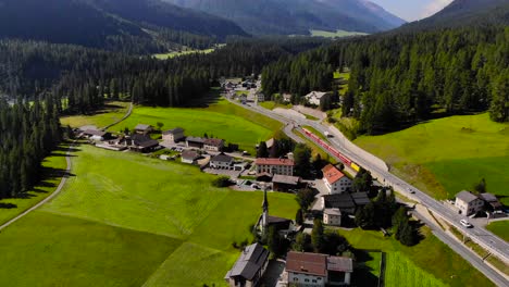 Aéreo:-Tren-Por-Una-Ciudad-Alpina-En-Un-Paisaje-Montañoso