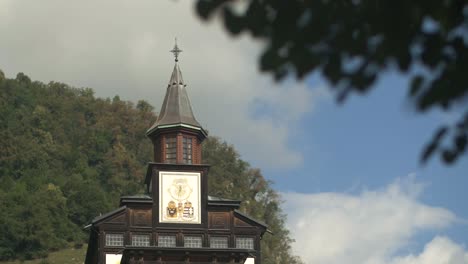 Memorial-church-of-Holy-Ghost-Javorca-in-Soca-valley,-Slovenia,-leaves-in-upper-right-corner