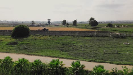 Aerial-view-of-a-man-riding-a-motorcycle-on-a-road-with-a-farm-in-the-background