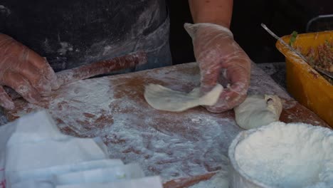 Using-a-rolling-pin-to-roll-the-dough,-fill-it-with-a-mixture-of-minced-pork-and-spring-onions,-close-up-shot-of-handmade-authentic-Xian-Bing,-Chinese-meat-pie-in-preparation