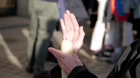 Closeup-of-an-Easter-candle-being-held-and-shielded-from-the-wind-by-hand-during-a-celebration-in-Madrid