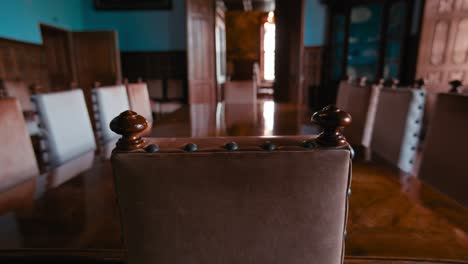 View-from-the-head-of-an-ornately-carved-dining-table-in-Trakošćan-Castle's-room,-Croatia,-with-focus-on-leather-chairs