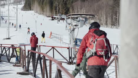 People-walking-towards-a-ski-lift-and-standing-in-line,-waiting-for-their-turns